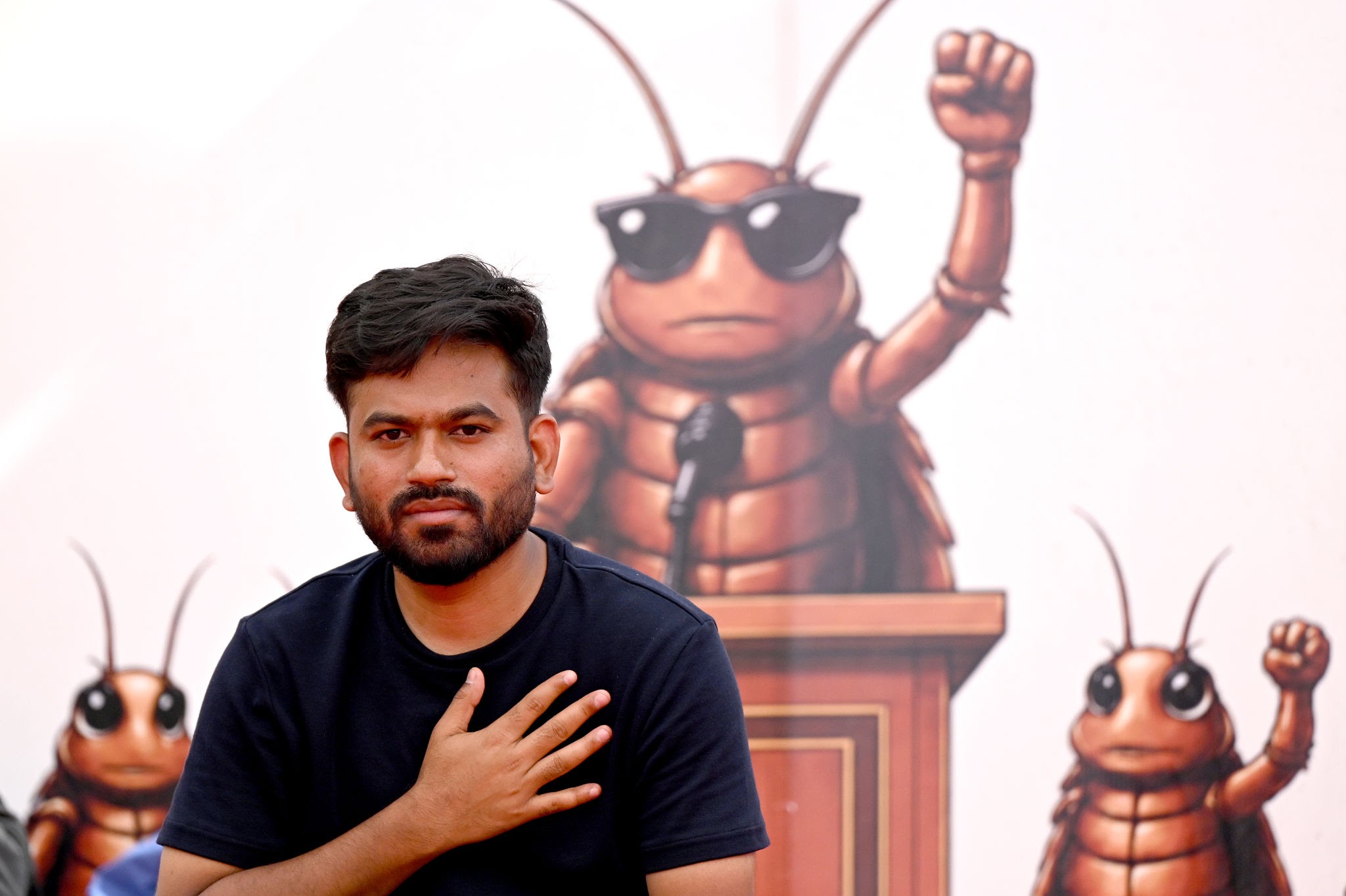 CJP founder Abhijeet Dipke sitting in front of a giant Cockroach mascot backdrop