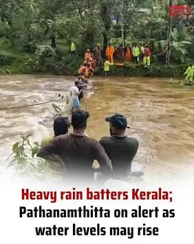Rescue operations underway as rescue workers help people cross a flooded river in Kerala