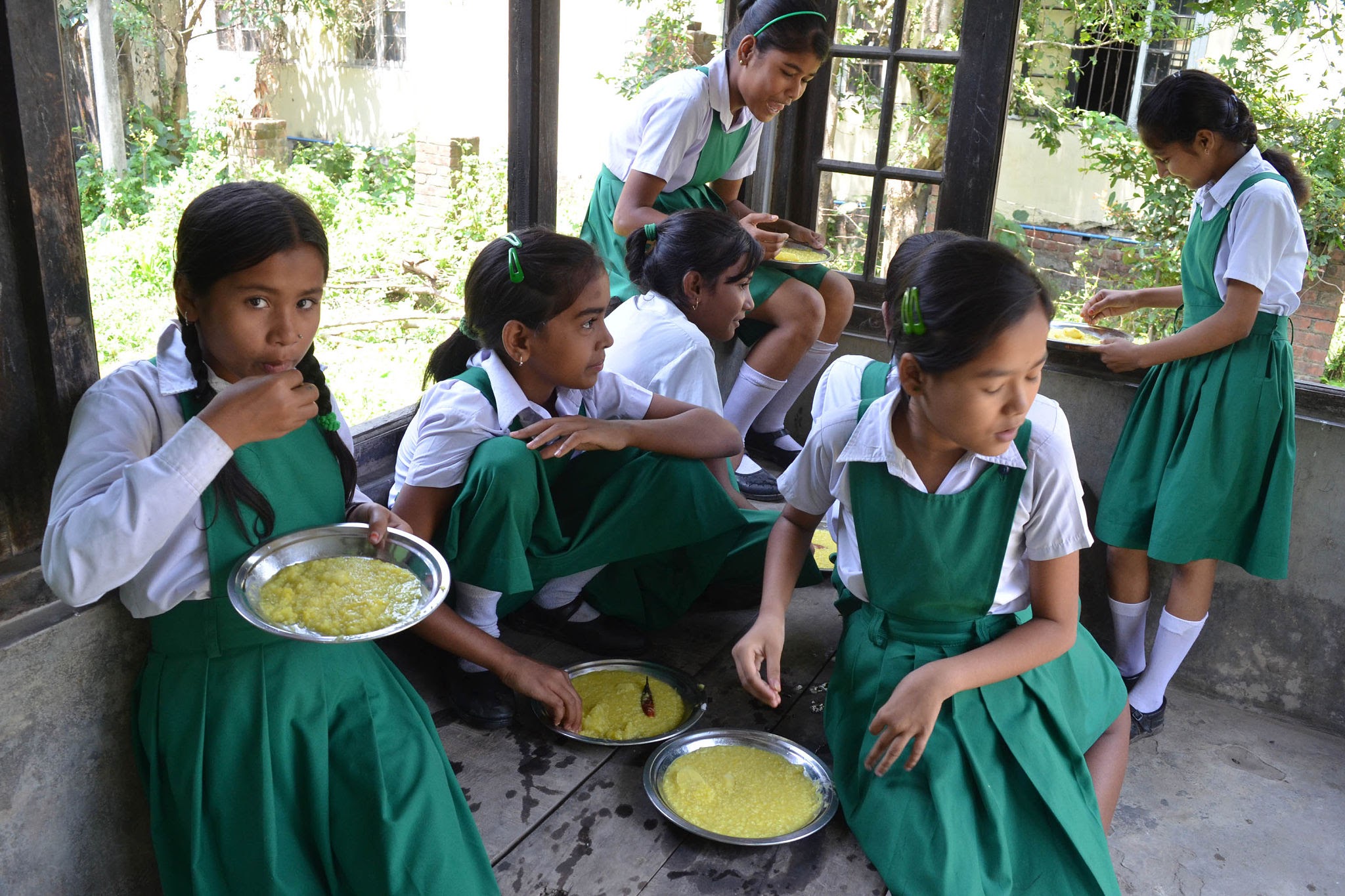 Schoolgirls sitting together eating freshly cooked rice and dal mid-day meal in school
