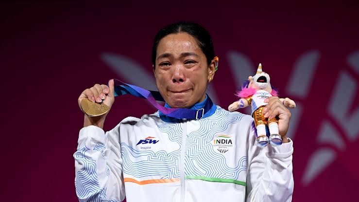 Mirabai Chanu crying tears of joy on the medal podium holding her Gold Medal at Glasgow 2026 Commonwealth Games