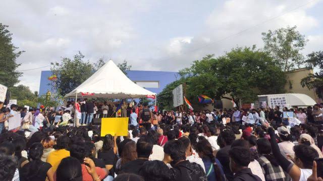 Massive crowd of student protesters gathered outdoors under tents with placards