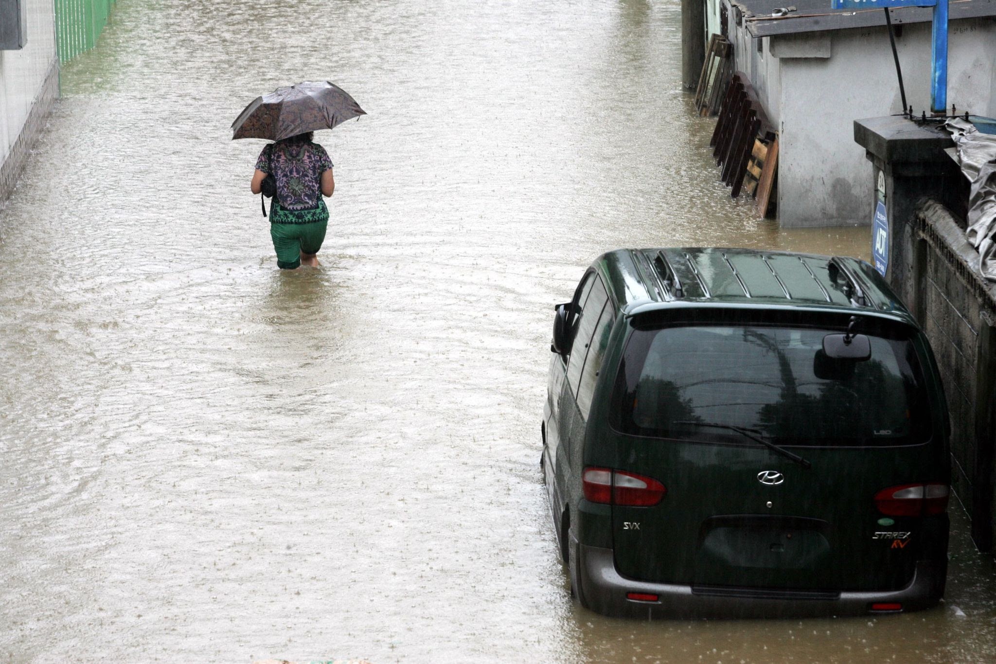 Urban flooding in Seoul during heavy Jangma monsoon rain with person wading through water